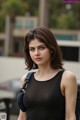 A woman in a black tank top is posing for a picture.