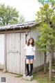 A woman standing in front of a wooden shed.