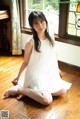 A woman in a white dress sitting on the floor.