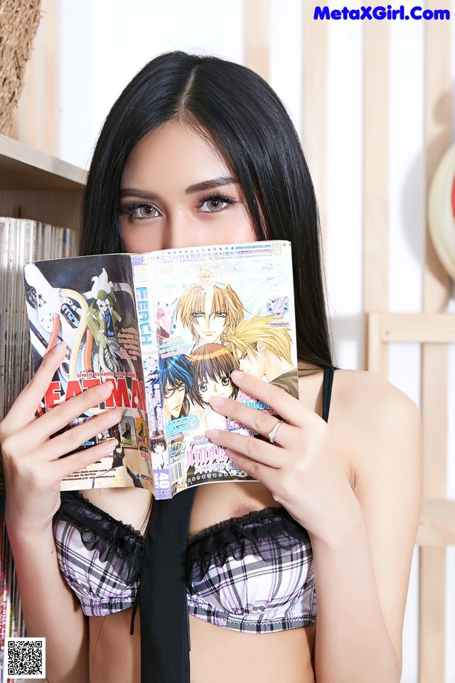 A woman holding a magazine in front of her face.