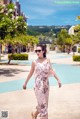 A woman walking down a sidewalk next to a swimming pool.