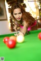 A woman in a pink bikini playing pool.