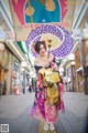 A woman in a kimono holding an umbrella on a city street.