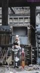 A woman in a black top and white pants standing in an abandoned building.