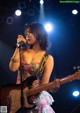 A woman playing a guitar and singing into a microphone.