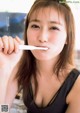 A woman holding a toothbrush in her mouth.