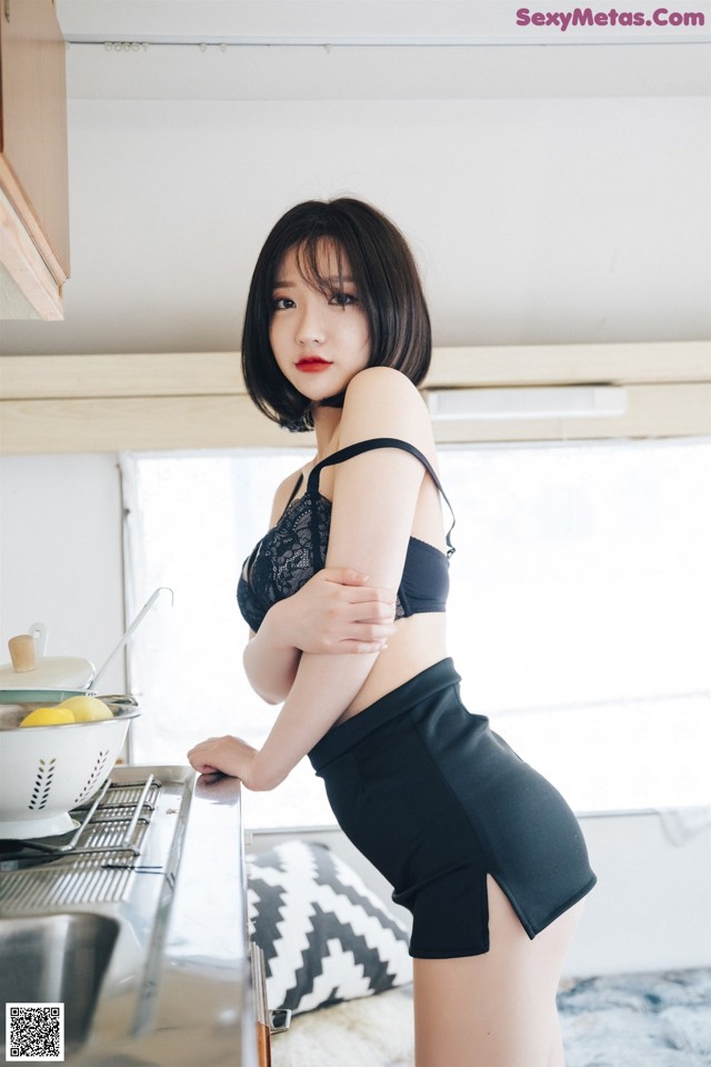 A woman standing in a kitchen next to a sink.