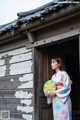 A woman in a kimono standing in front of a wooden building.